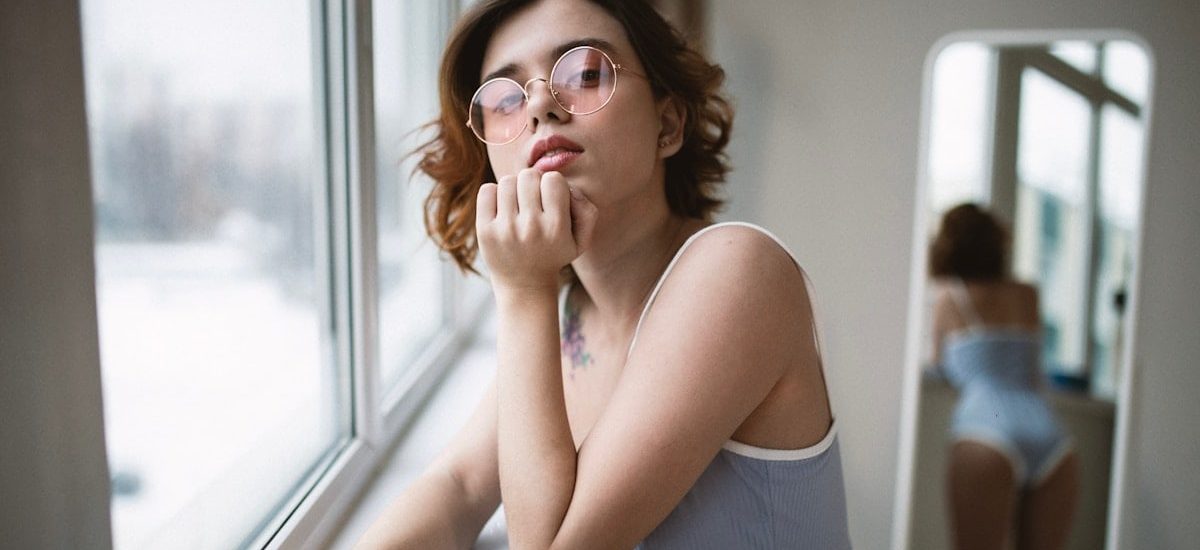 a woman with glasses looking out of a window