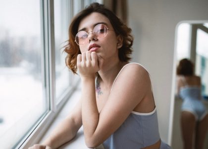 a woman with glasses looking out of a window