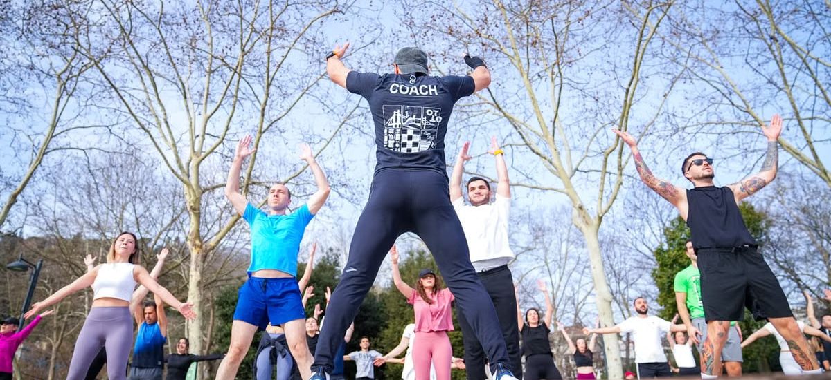 Group exercise session in a sunny Istanbul park led by a fitness coach outdoors.